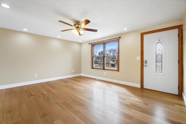 foyer with baseboards, light wood-style floors, and a textured ceiling