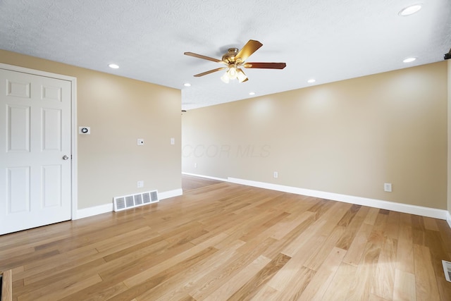 empty room featuring a ceiling fan, light wood-style flooring, baseboards, and visible vents