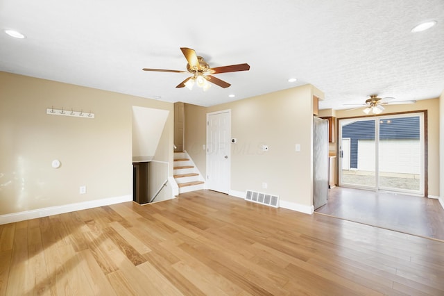 spare room with stairs, light wood-style flooring, baseboards, and visible vents