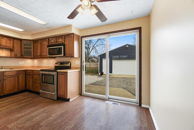 kitchen with baseboards, dark wood finished floors, light countertops, brown cabinetry, and stainless steel appliances