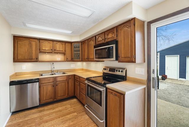 kitchen featuring a sink, stainless steel appliances, brown cabinets, and light countertops