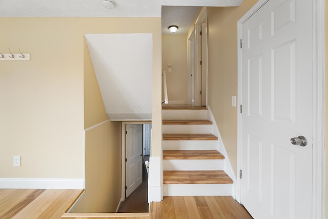 stairway with baseboards and wood finished floors