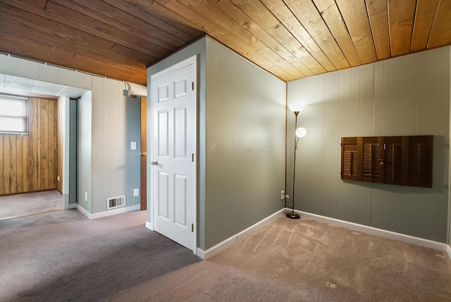 unfurnished room featuring visible vents, carpet floors, baseboards, and wooden ceiling