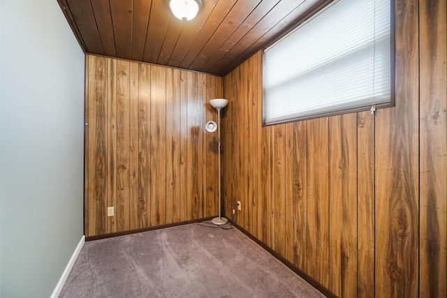 carpeted spare room with baseboards, wooden walls, and wooden ceiling