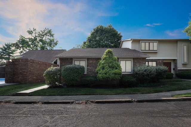 view of front of house featuring brick siding and roof with shingles