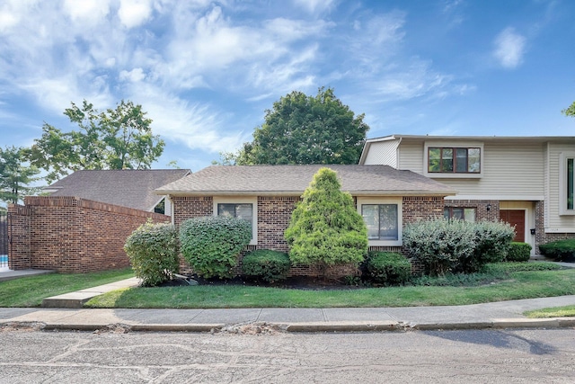 tri-level home featuring a shingled roof and brick siding