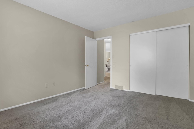 unfurnished bedroom with baseboards, carpet, visible vents, and a closet