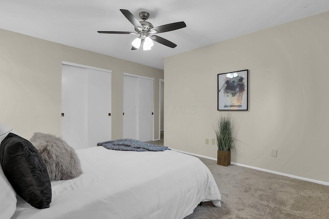 bedroom with baseboards, carpet flooring, a ceiling fan, and multiple closets