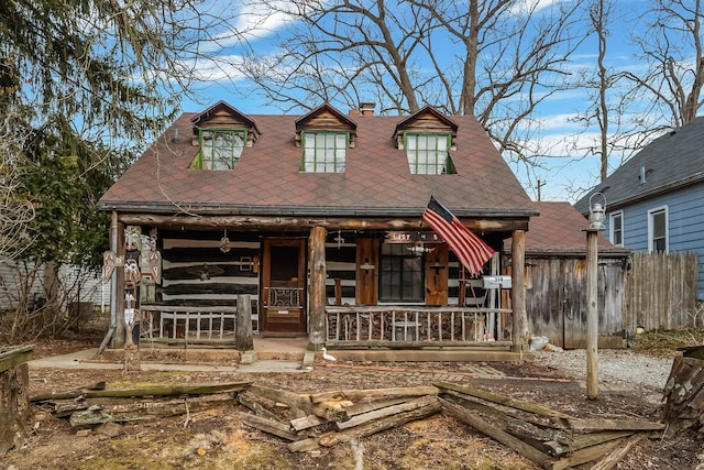 view of front of home featuring a porch, fence, roof with shingles, and a chimney