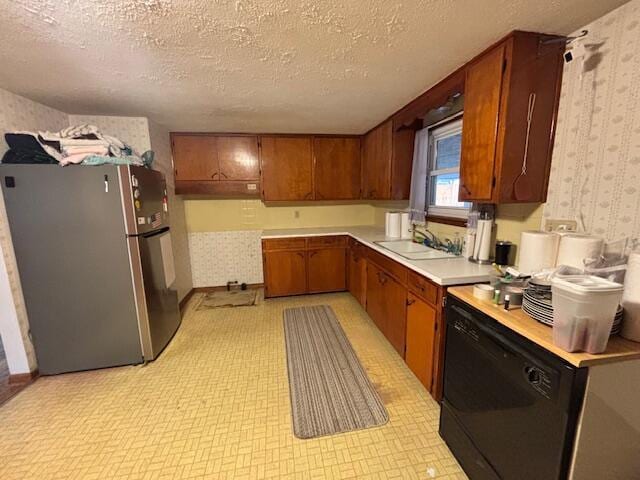 kitchen with wallpapered walls, black dishwasher, freestanding refrigerator, light countertops, and a sink