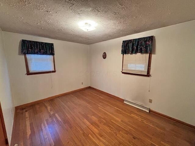 empty room featuring visible vents, baseboards, a textured ceiling, and hardwood / wood-style floors