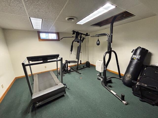 exercise area featuring a drop ceiling, visible vents, and baseboards