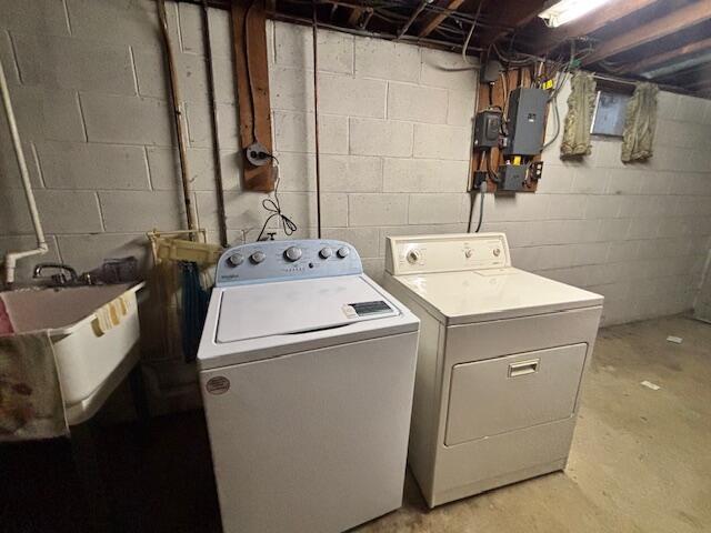 washroom with laundry area, washing machine and dryer, electric panel, and a sink