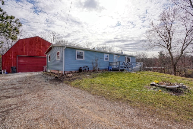 view of front of house featuring an outbuilding, a detached garage, dirt driveway, and a front yard