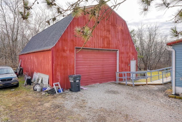 view of barn featuring driveway and fence