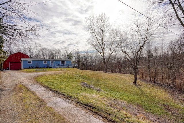 exterior space with a garage, dirt driveway, a front lawn, and a porch