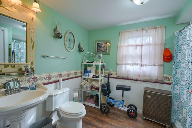 full bath featuring toilet, curtained shower, a sink, and wood finished floors