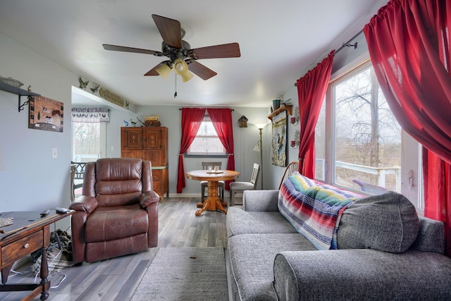 living room with baseboards, a ceiling fan, and wood finished floors