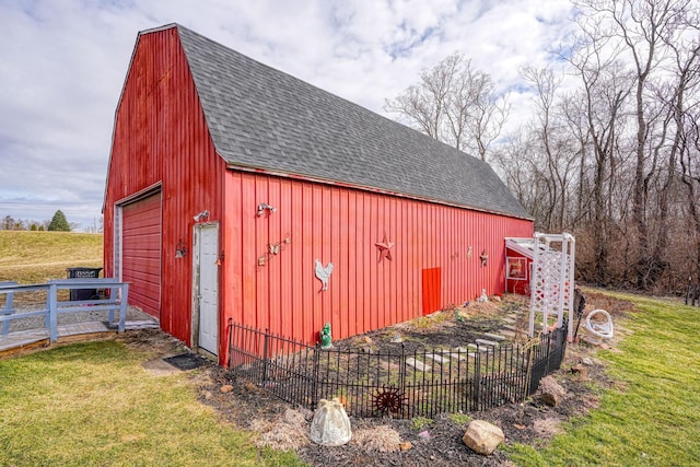 view of barn with fence and a lawn