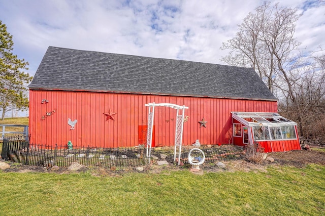 view of barn with fence and a lawn