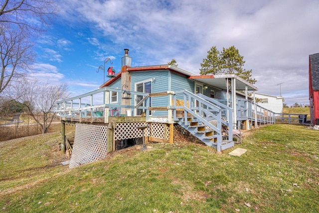 rear view of property featuring a deck, a lawn, and stairs