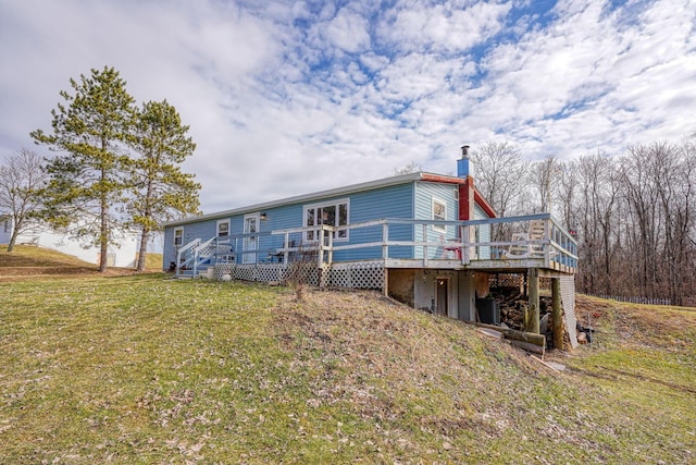 back of house featuring a yard, a chimney, and a wooden deck