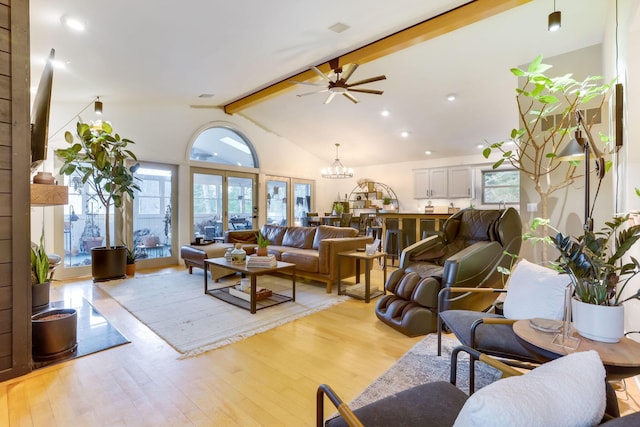 living room featuring lofted ceiling with beams, light wood-style flooring, and ceiling fan with notable chandelier