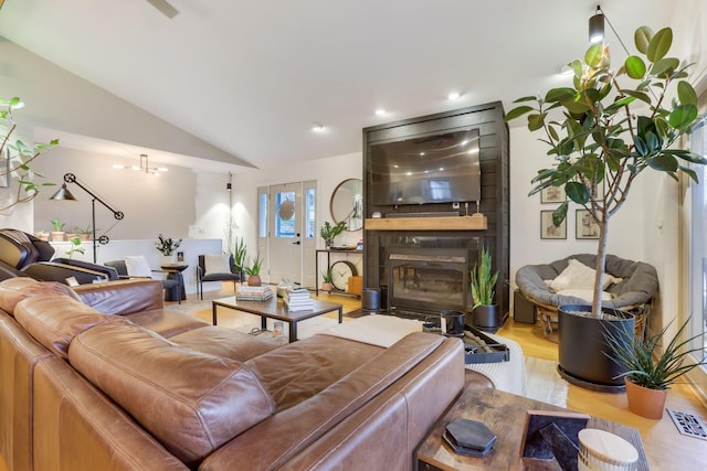 living area with lofted ceiling, a large fireplace, visible vents, and wood finished floors