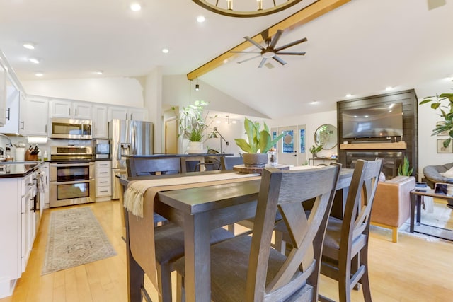 kitchen featuring stainless steel appliances, dark countertops, white cabinetry, light wood-type flooring, and beamed ceiling