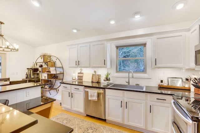 kitchen featuring dark countertops, appliances with stainless steel finishes, decorative backsplash, and a sink