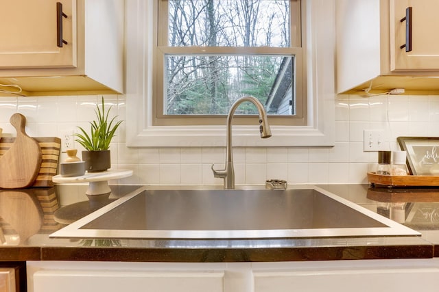 interior details with dark countertops, a sink, and backsplash