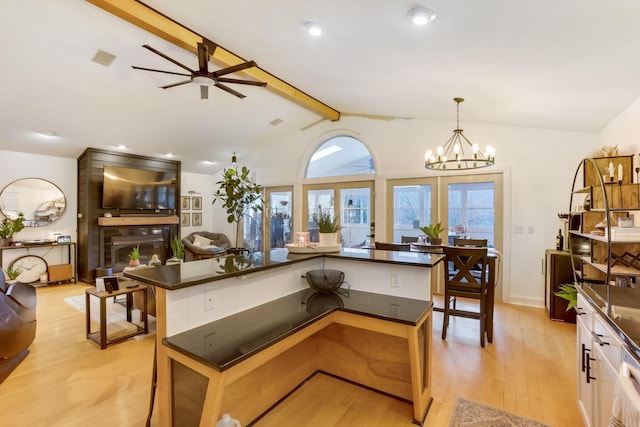 kitchen with dark countertops, open floor plan, a large fireplace, and vaulted ceiling with beams