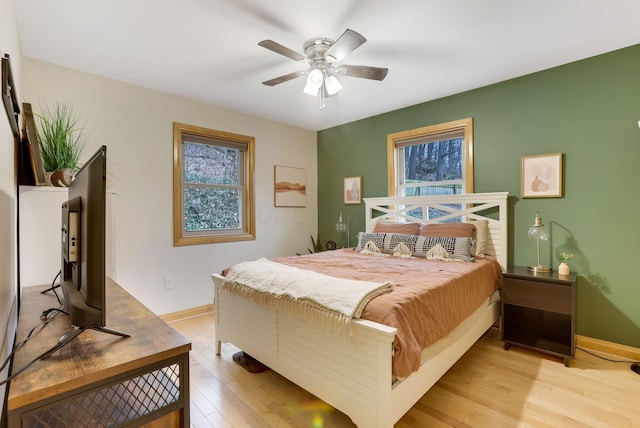 bedroom with light wood-style flooring, baseboards, and a ceiling fan