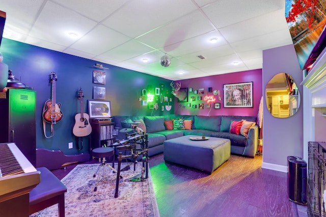 living area featuring wood finished floors, a paneled ceiling, and baseboards