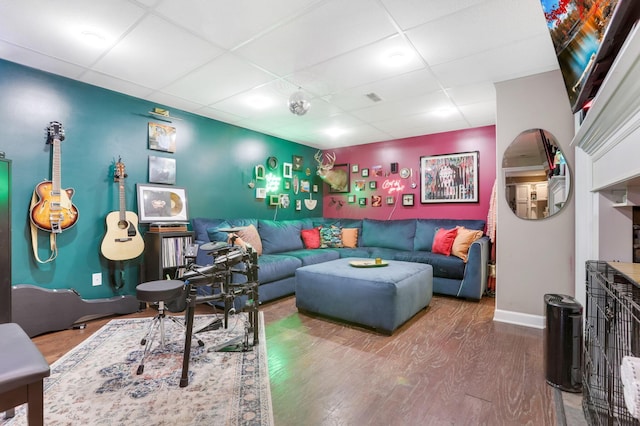 living room with a paneled ceiling, baseboards, and wood finished floors