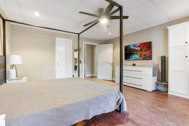 bedroom featuring ceiling fan, wood finished floors, and a paneled ceiling