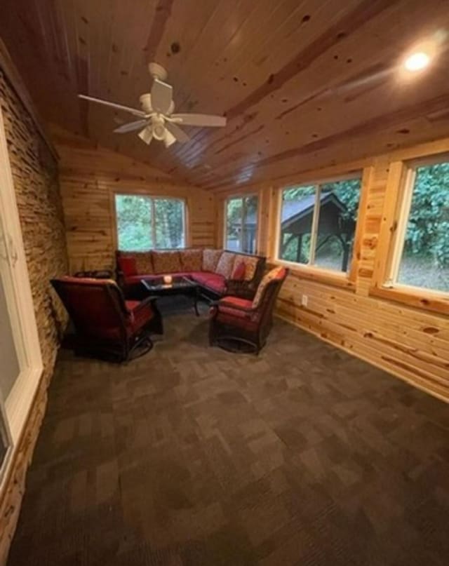 living area featuring lofted ceiling, wooden walls, wood ceiling, and a healthy amount of sunlight