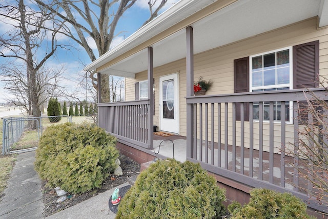 doorway to property with a porch and fence