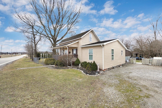 view of side of home with a yard, fence, driveway, and a porch