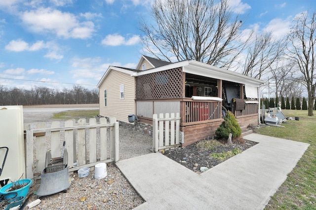 view of side of home with covered porch and fence