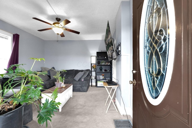 interior space with ceiling fan, visible vents, a textured ceiling, and light colored carpet