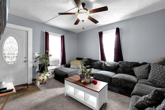 living area featuring a textured ceiling, ceiling fan, plenty of natural light, and carpet flooring