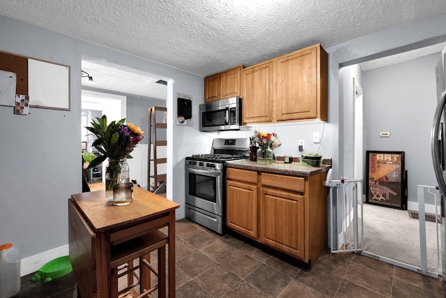 kitchen featuring appliances with stainless steel finishes, dark countertops, and a textured ceiling