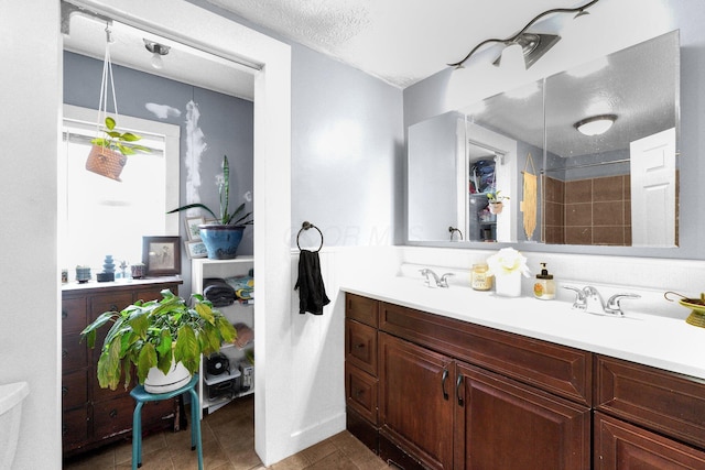 bathroom with a shower, vanity, a textured ceiling, and tile patterned floors