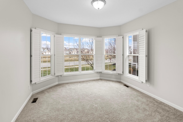 carpeted empty room featuring visible vents and baseboards