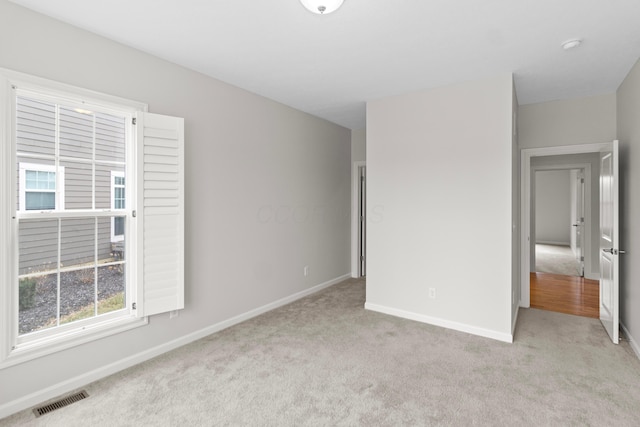 unfurnished bedroom with light carpet, visible vents, and baseboards