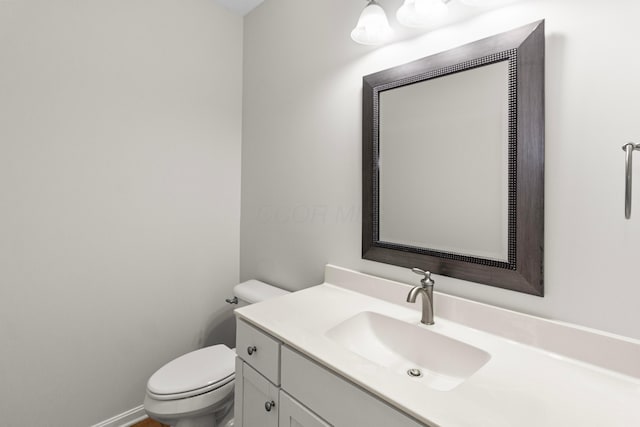 bathroom featuring toilet, baseboards, and vanity