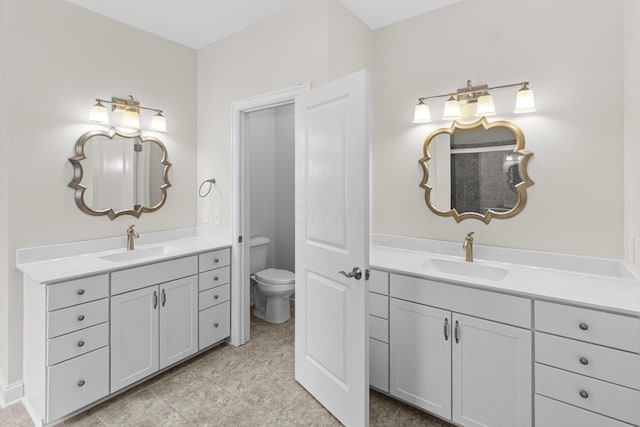 bathroom featuring toilet, two vanities, and a sink