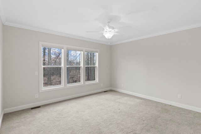 empty room with baseboards, visible vents, a ceiling fan, crown molding, and carpet floors