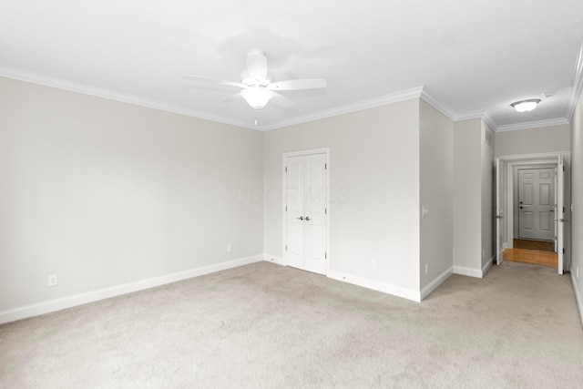 unfurnished room featuring light carpet, ornamental molding, a ceiling fan, and baseboards